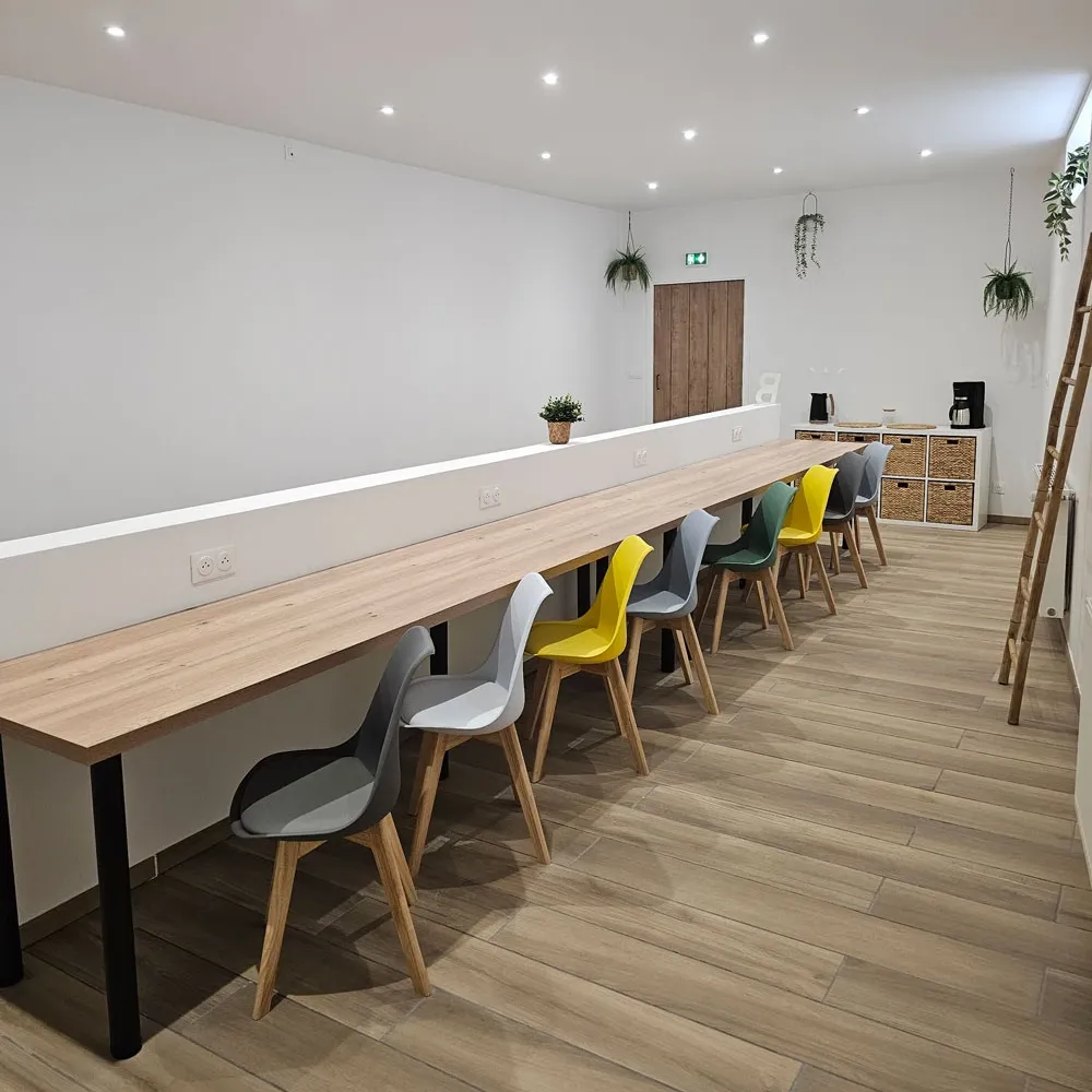 Espace de coworking convivial avec prises électriques intégrées, parfait pour le télétravail ou les sessions collaboratives chez Brin d’Amour.